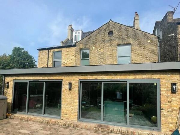 Solar film on two sets of grey sliding doors on a brick rear extension
